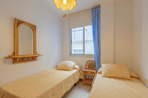 Un dormitorio con dos camas y un espejo y una ventana. en Casa Leila, en Puerto Naos