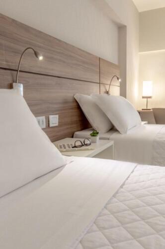 a bedroom with two beds and a table with glasses at Intercity Maceio in Maceió