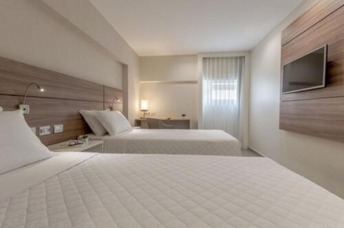 a hotel room with two beds and a television at Intercity Maceio in Maceió