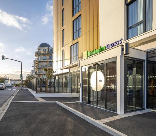 a building with a sign on the side of a street at Holiday Inn Express Paris - Poissy by IHG in Poissy