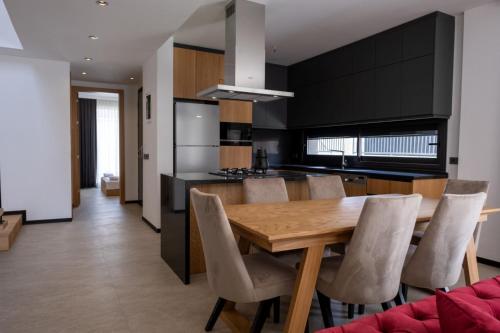 a kitchen and dining room with a wooden table and chairs at Villa merkez havuzlu odalarbanyolu in Cesme