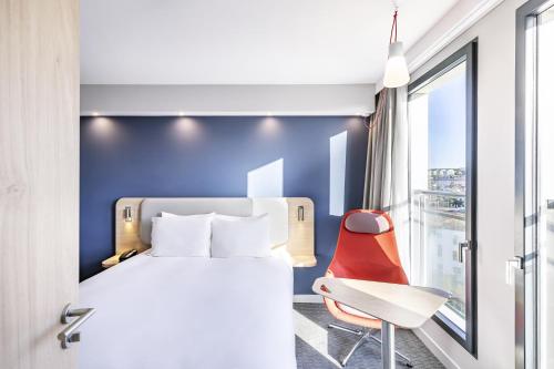 a hotel room with a bed and a chair at Holiday Inn Express Paris - Poissy by IHG in Poissy