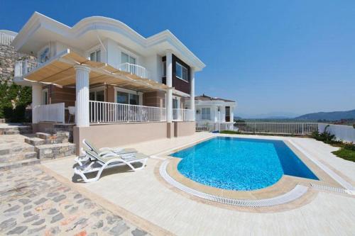 a villa with a swimming pool in front of a house at Villa Carolina The Royal Links Sarigerme, Ortaca in Sarigerme