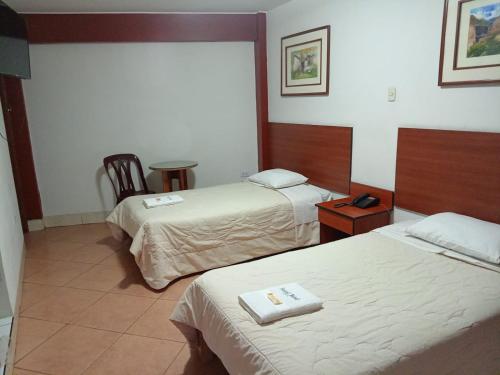 a hotel room with two beds and a table at Hostal Bond in Huaraz