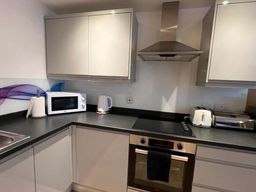 a kitchen with a microwave oven and a stove at Glastonbury Harmony, Split-Level 1 bedroom Apartment in Glastonbury