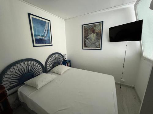 a bedroom with a white bed and a flat screen tv at Charmant appartement en rez-de-chaussée à 150m de la plage in Saint-Georges-de-Didonne