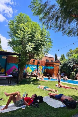 a group of people laying on the grass near a pool at Gorilla Hostel in Mendoza