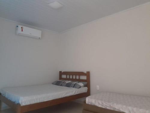 two beds in a room with white walls at Pousada Chalé Boracéia in Boracéia