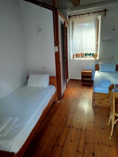 two beds in a room with a wooden floor at Sotos pension in Skopelos Town