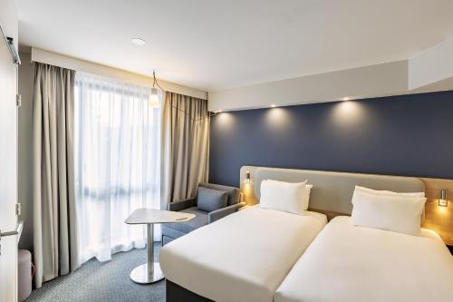 a hotel room with two beds and a window at Holiday Inn Express Paris - Poissy by IHG in Poissy
