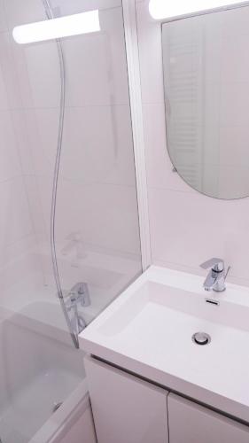 une salle de bain blanche avec une douche et un lavabo dans l'établissement Appartement dans quartier pittoresque, à Caen