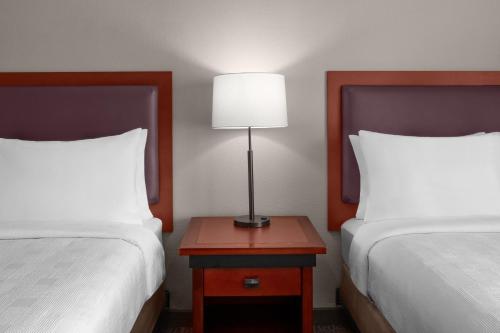 a bedroom with two beds and a table with a lamp at Larkspur Landing Extended Stay Suites Roseville in Roseville