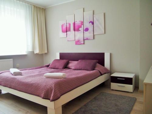 Schlafzimmer mit einem Bett mit lila Bettwäsche und rosafarbenen Gemälden in der Unterkunft Hotel Dom Polonii in Ostróda