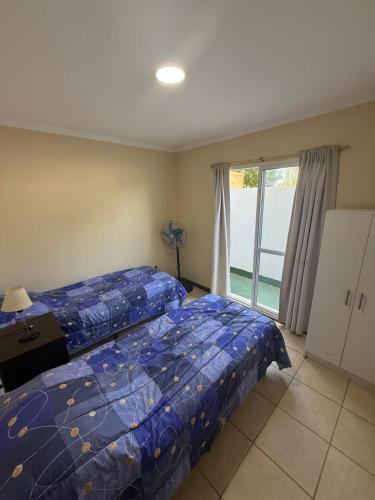 a bedroom with a bed with a blue comforter and a window at Departamento en Ramallo in Ramallo