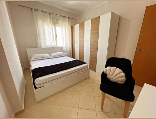 een kleine slaapkamer met een bed en een stoel bij Bliss Home in Vlorë