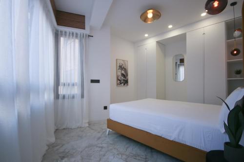 a white bedroom with a bed and a window at LC Apartaments Centro Trinidad in Castellón de la Plana