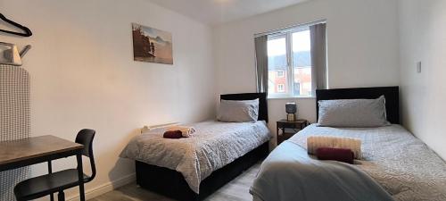 a bedroom with two beds and a table and a window at 4 beds spacious Apartment, with Parking & WIFI, CHAFFORD HUNDRED, near station & shopping, long stays! in West Thurrock