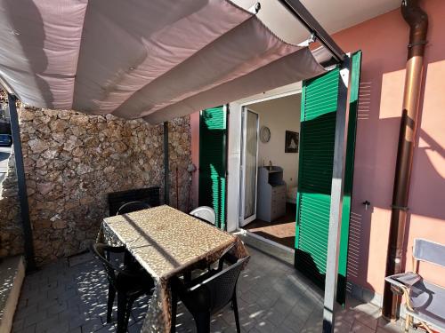 a patio with a table and some green shutters at Casa SERGE vista mare con ampio terrazzo privato in Bergeggi