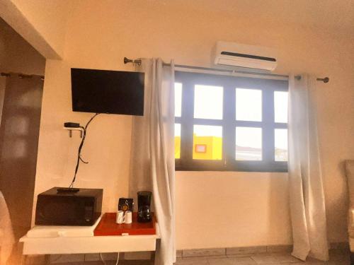 a living room with a window with a television and a table at Los Vientos Hotel in Bahía de los Ángeles