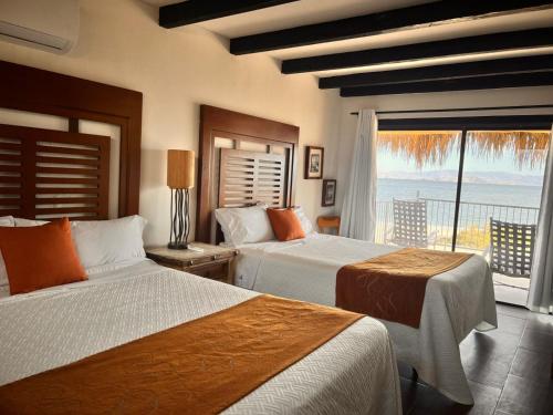 two beds in a room with a view of the ocean at Los Vientos Hotel in Bahía de los Ángeles