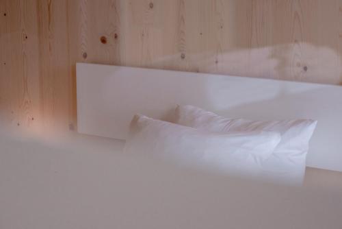 a white bed with white pillows and a mirror at Bader Hotel in Parsdorf