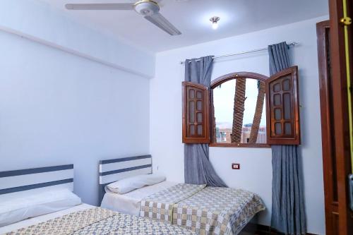 twee bedden in een kamer met een raam bij Habiba Apartment in Luxor