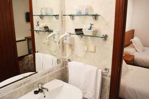 y baño con lavabo y espejo. en Pensión Residencia Fornos en Santiago de Compostela