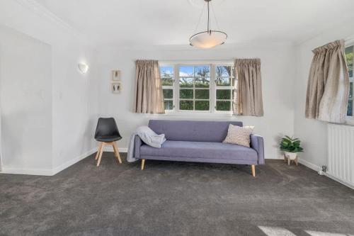 a living room with a purple couch and windows at Thermal Adventure Retreat in Rotorua