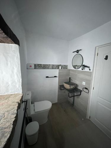 a white bathroom with a toilet and a sink at Finca Esmeralda in Zahora