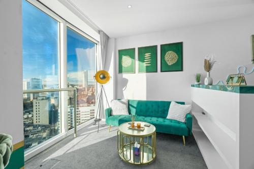 a living room with a green couch and a table at Emerald haven - Birmingham skyline view in Birmingham