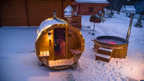 a dog house in the snow next to a barrel at Górskie Wytchnienie Domki Karkonosze in Piechowice