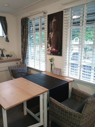 a dining room with a table and chairs and windows at Prive tuinhuis B&B Elly in Sint Pancras