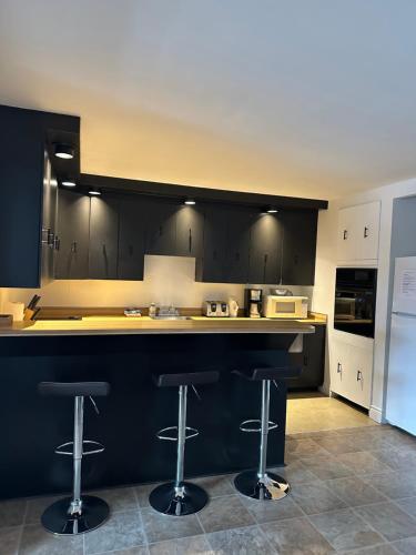 a kitchen with black cabinets and two bar stools at 881 L'APPARTEMENT FAMILIAL "Central" in Quebec City