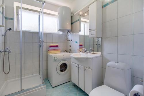 a bathroom with a toilet sink and a washing machine at Apartment Bambi in Mali Lošinj