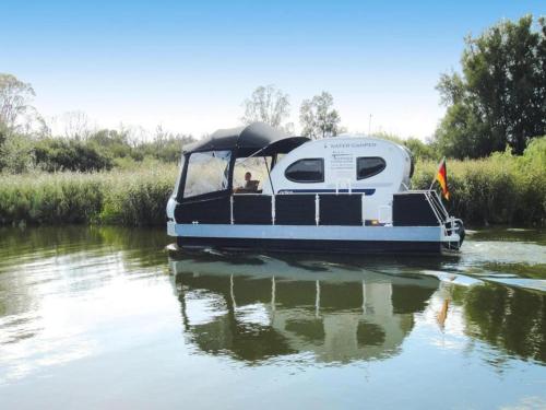 a boat on a river with a person on it at Houseboat on the Peene in Demmin in Verchen