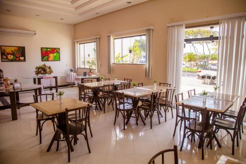 a restaurant with tables and chairs and windows at Hotel Oceania in Eunápolis