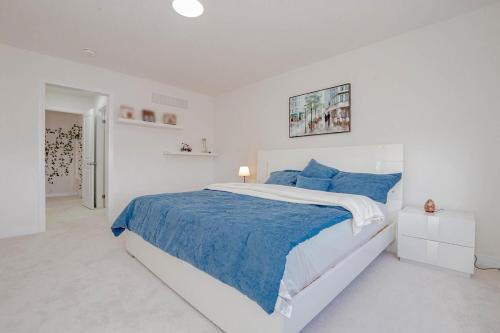 a white bedroom with a large bed with blue pillows at Amazing Home in Niagra Region in Thorold