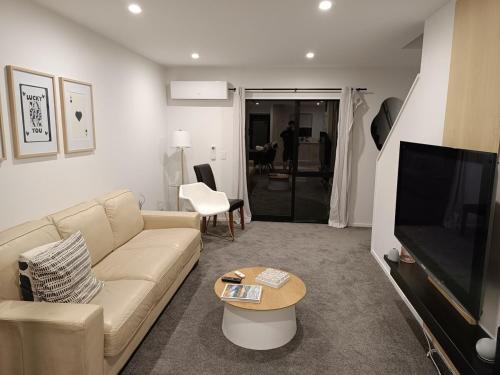 a living room with a couch and a flat screen tv at A Quiet Modern and Brand New Gem in Lower Hutt