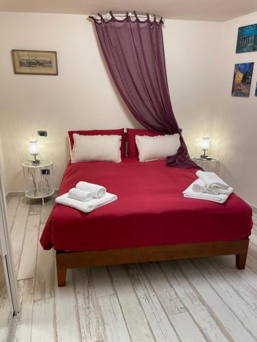 a bedroom with a red bed with two towels on it at Rosari Spada Suite sec XVI in Spoleto