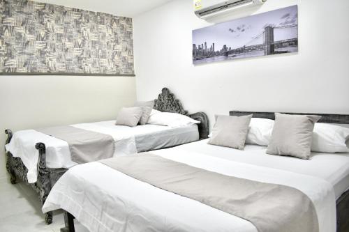 duas camas em um quarto com paredes brancas em SANTO RIO SUITE Hotel em Santa Marta