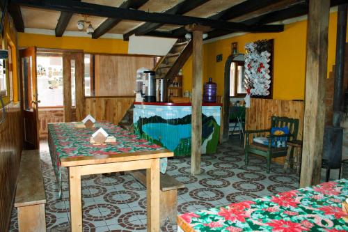 a room with a table and a kitchen with yellow walls at Hostal Cloud Forest in Chugchilán