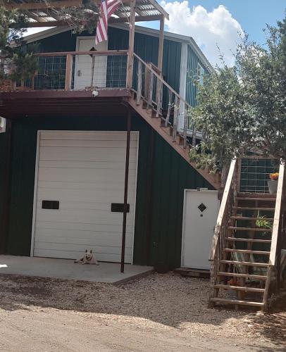 a dog laying on the ground in front of a garage at Boulderdash Birdhouse Studio in Bandera