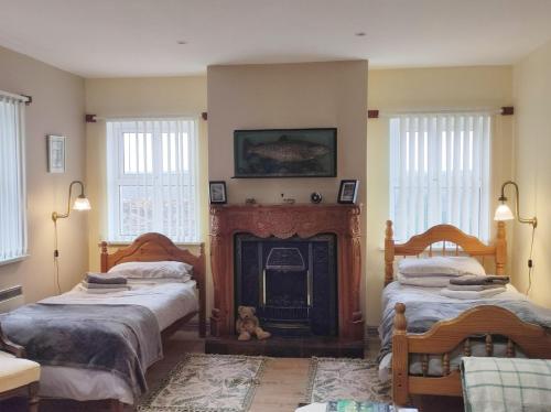 a living room with two beds and a fireplace at Ben Levy House Rental Suite, Clonbur Village in Clonbur