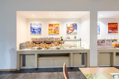a restaurant with a counter with plates of food at Meditur Hotel Udine Nord in Udine