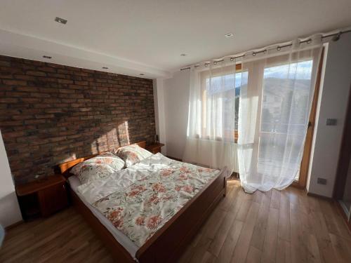 a bedroom with a brick wall and a bed at Apartament Florynka in Florynka