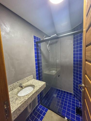 a blue tiled bathroom with a sink and a shower at Condomínio Apoena in São Sebastião