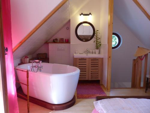 a bathroom with a white tub and a sink at La Flore De Lys in Saint-Jouin-Bruneval