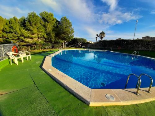 a swimming pool in a yard with a green lawn at Pinada Golf Apartment in Orihuela Costa