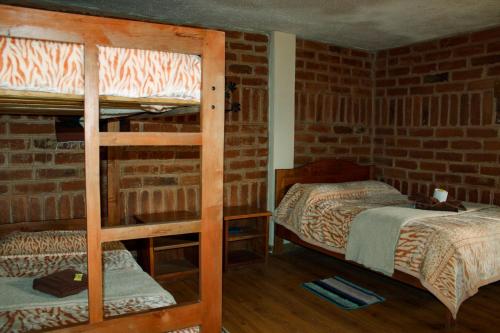 two bunk beds in a room with a brick wall at Hostal Cloud Forest in Chugchilán
