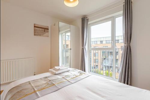 a bedroom with a bed and a large window at Modern 2 Bed Flat with Balcony, Easy London Access in London